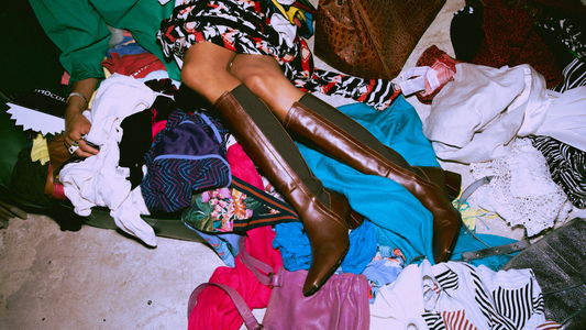 Lady laying in a big pile of vintage clothing